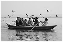 Indian tourists on rawboat surrounded by birds. Varanasi, Uttar Pradesh, India ( black and white)
