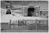 Sadhu sitting next to shrine and laundry. Varanasi, Uttar Pradesh, India (black and white)