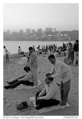Head masseurs and Mumbai skyline at sunset,  Chowpatty Beach. Mumbai, Maharashtra, India (black and white)