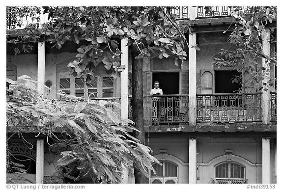 Facade with balconies and man reading. Mumbai, Maharashtra, India (black and white)
