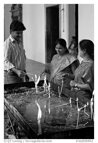 Man and two women burning candles, Basilica of Bom Jesus, Old Goa. Goa, India (black and white)