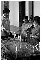 Man and two women burning candles, Basilica of Bom Jesus, Old Goa. Goa, India (black and white)
