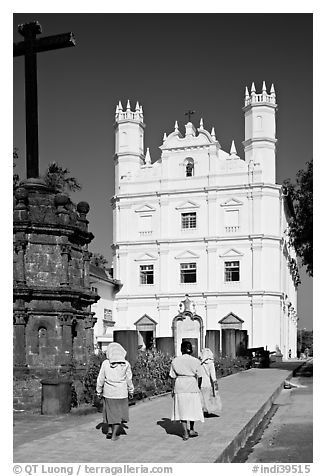 Women walking towards Church of St Francis of Assisi, afternoon, Old Goa. Goa, India (black and white)