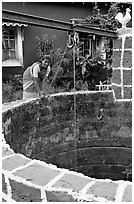 Woman retrieving water from well, Panaji. Goa, India (black and white)