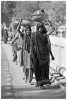 Women walking in line carrying baskets on heads. Khajuraho, Madhya Pradesh, India (black and white)