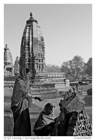 Women worshipping image with temple spire behind. Khajuraho, Madhya Pradesh, India (black and white)