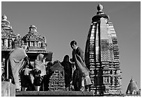 Women worshipping image with of Vahara and Lakshmana temples behind. Khajuraho, Madhya Pradesh, India (black and white)