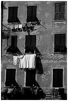 Typical terra cotta facade with hanging laundry and green shutters, Vernazza. Cinque Terre, Liguria, Italy (black and white)