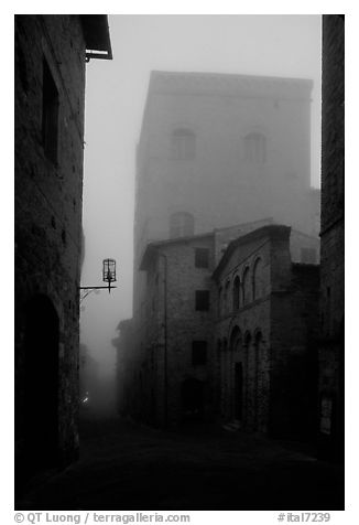 Street and medieval tower at dawn in the fog. San Gimignano, Tuscany, Italy (black and white)