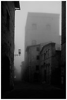 Street and medieval tower at dawn in the fog. San Gimignano, Tuscany, Italy ( black and white)