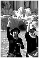 Asian tourists toss a coin over their shoulder into the Trevi Fountain. Rome, Lazio, Italy ( black and white)