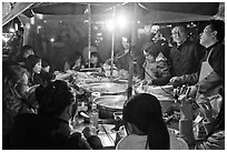 People eating noodles in a tent at night. Seoul, South Korea (black and white)