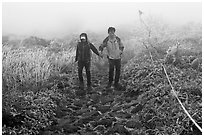 Couple hiking holding hands in fog. Jeju Island, South Korea (black and white)