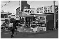 Haeneyo woman walking towards seafood restaurant. Jeju Island, South Korea (black and white)