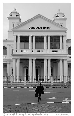 Man in suit crossing streets towards court building. George Town, Penang, Malaysia