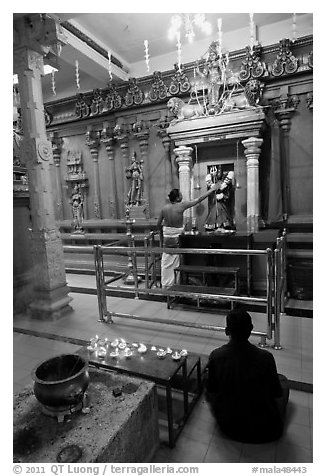 Holy man tends to altar, Hindu temple. George Town, Penang, Malaysia (black and white)