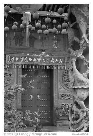 Red paper lanters, door, and stone carved wall, Hainan Temple. George Town, Penang, Malaysia (black and white)