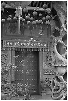 Red paper lanters, door, and stone carved wall, Hainan Temple. George Town, Penang, Malaysia (black and white)