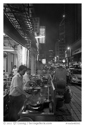 Cooks preparing food on Chinatown street at night. Kuala Lumpur, Malaysia (black and white)