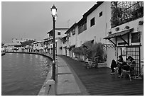 Women relaxing in front of riverside house, dusk. Malacca City, Malaysia ( black and white)