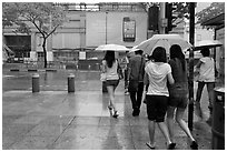 Women walking under unbrella during downpour. Singapore (black and white)