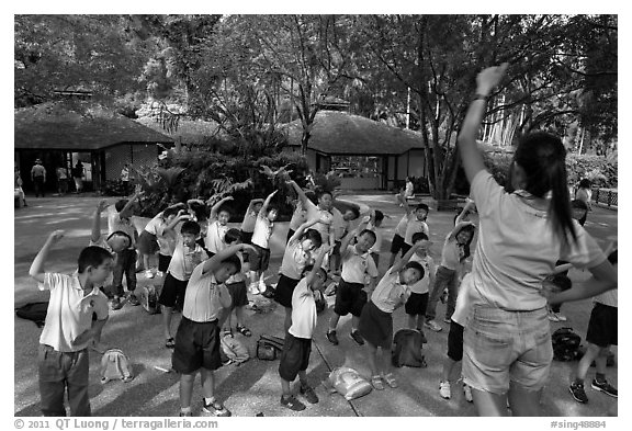Schoolchildren doing gymnastics in  Singapore Botanical Gardens. Singapore (black and white)