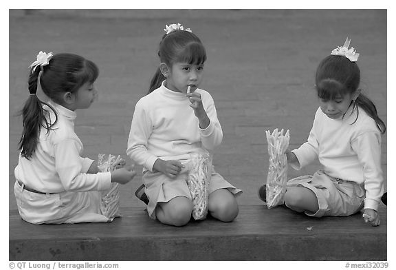Three little girls in school uniform eating snack. Guadalajara, Jalisco, Mexico