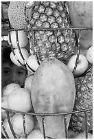 Boy peers from behind fruits offered at a juice stand, Tlaquepaque. Jalisco, Mexico (black and white)