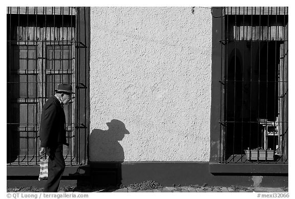 Elderly man walking along a colorful wall, Tlaquepaque. Jalisco, Mexico (black and white)