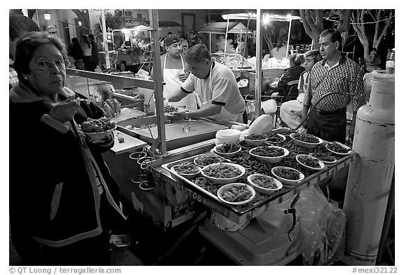 Woman eating by a street food stand , Tlaquepaque. Jalisco, Mexico (black and white)