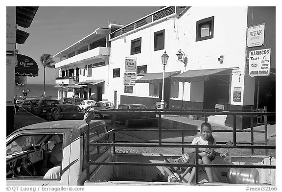 Girl riding in the back of pick-up truck in a street close to ocean, Puerto Vallarta, Jalisco. Jalisco, Mexico (black and white)