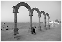 Boy standing by the Malecon arches at dusk, Puerto Vallarta, Jalisco. Jalisco, Mexico ( black and white)