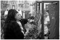 Women placing flowers in front of a Saint figure. Zacatecas, Mexico ( black and white)