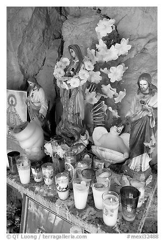 Religious figures and candles in roadside chapel. Mexico (black and white)