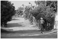 Man on horse going down a village street. Mexico ( black and white)