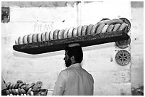 Man carrying many loafes of bread on his head. Jerusalem, Israel (black and white)