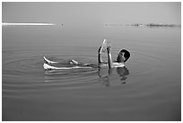 Visitor reading while floating in the Dead Sea. Israel (black and white)