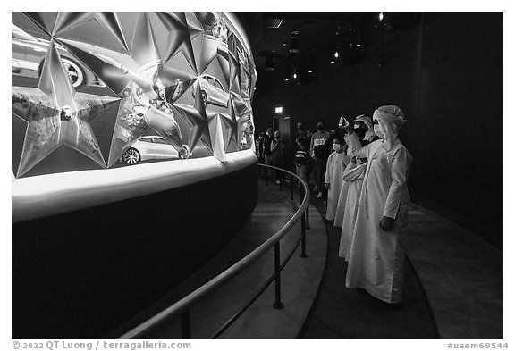 Visitors in Arab dress looking at curved wall of stars with projected media, USA Pavilion. Expo 2020, Dubai, United Arab Emirates (black and white)