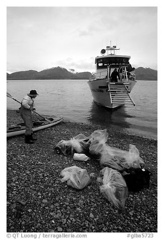Kayaker standing with gear wrapped in plastic bags after drop-off. Glacier Bay National Park, Alaska