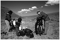 Backpackers breaking camp and readying backpacks. Lake Clark National Park, Alaska (black and white)
