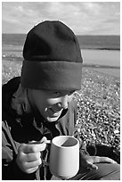 Backpacker drinking from a cup, with mosquitoes on her hat. Lake Clark National Park, Alaska (black and white)