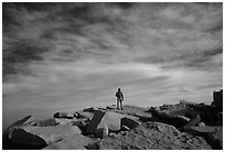 Hiker standing on flat rocks on top of Mt Whitney summit. Sequoia National Park, California (black and white)