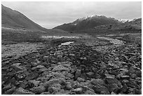 Field of angular rocks alternating with moss and snowy mountains. Gates of the Arctic National Park ( black and white)