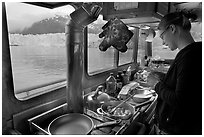 Woman preparing a breakfast aboard small tour boat. Glacier Bay National Park, Alaska, USA. (black and white)