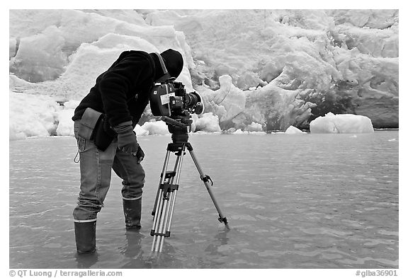 Cameraman standing in water at the base of Reid Glacier. Glacier Bay National Park (black and white)