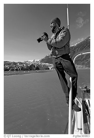 Photographer perched on boat in Reid Inlet. Glacier Bay National Park (black and white)