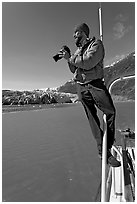 Photographer perched on boat in Reid Inlet. Glacier Bay National Park, Alaska, USA. (black and white)