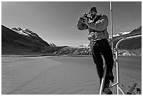 Photographer perched on boat with Reid Glacier behind. Glacier Bay National Park ( black and white)