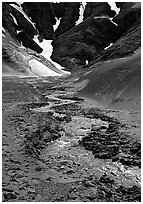 Stream flows from the verdant hills into the barren floor of the Valley of Ten Thousand smokes. Katmai National Park ( black and white)