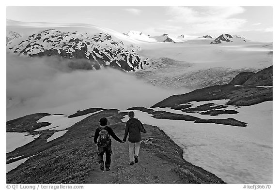 Couple hiking down Harding Icefied trail, late afternoon. Kenai Fjords National Park, Alaska, USA.